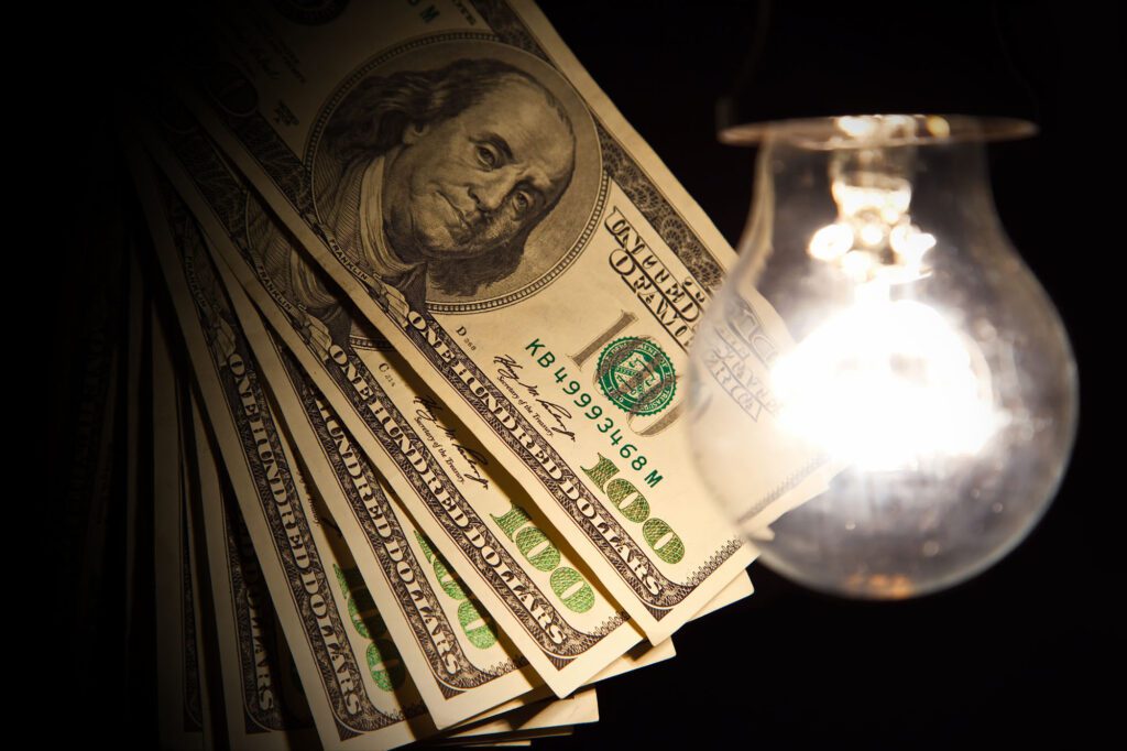 Hanging light bulb dangle on a wire illuminating bank notes