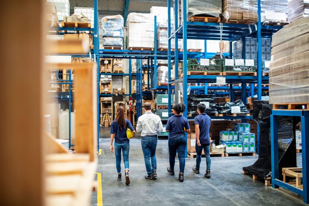 Group of warehouse workers walking through storage racks