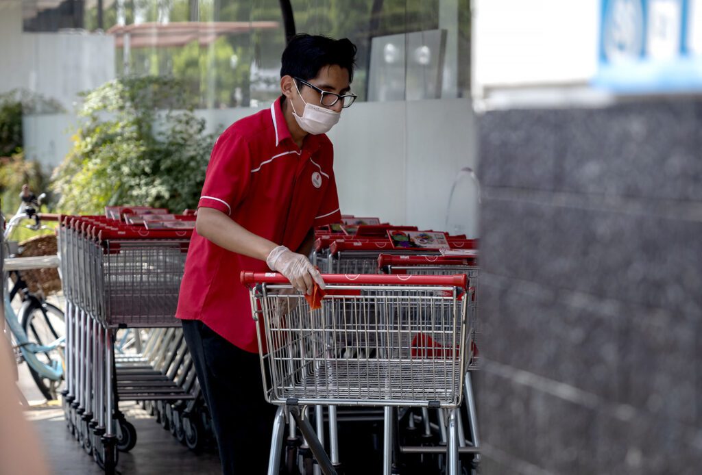 Supermarket worker disinfecting carts COVID-19 times