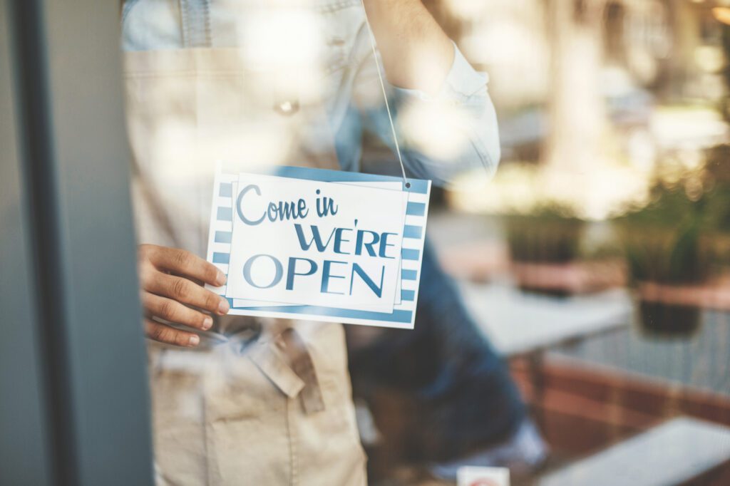 Man placing open sign on cafe door