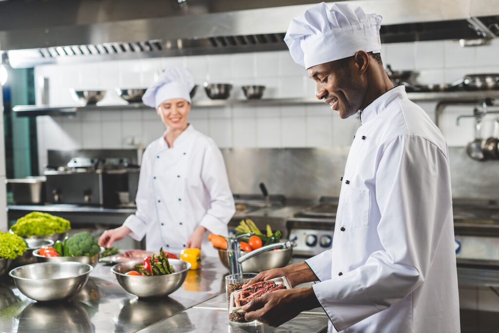 smiling african american chef holding tray with raw meat at restaurant kitchen