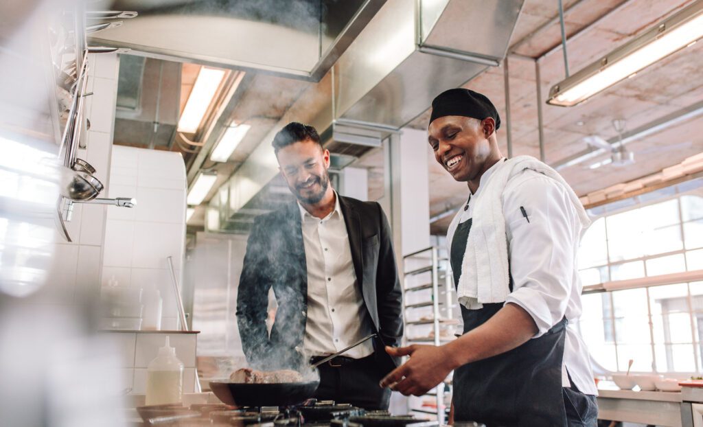 Restaurant manager with chef cooking in kitchen