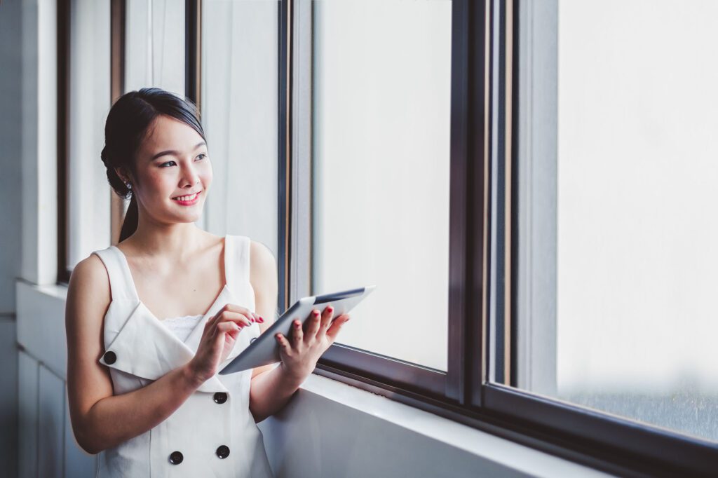 portrait young asian business woman in office using tablet