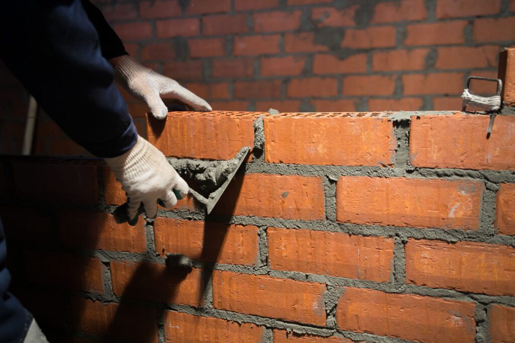 Closeup hand professional construction worker laying bricks in new industrial site