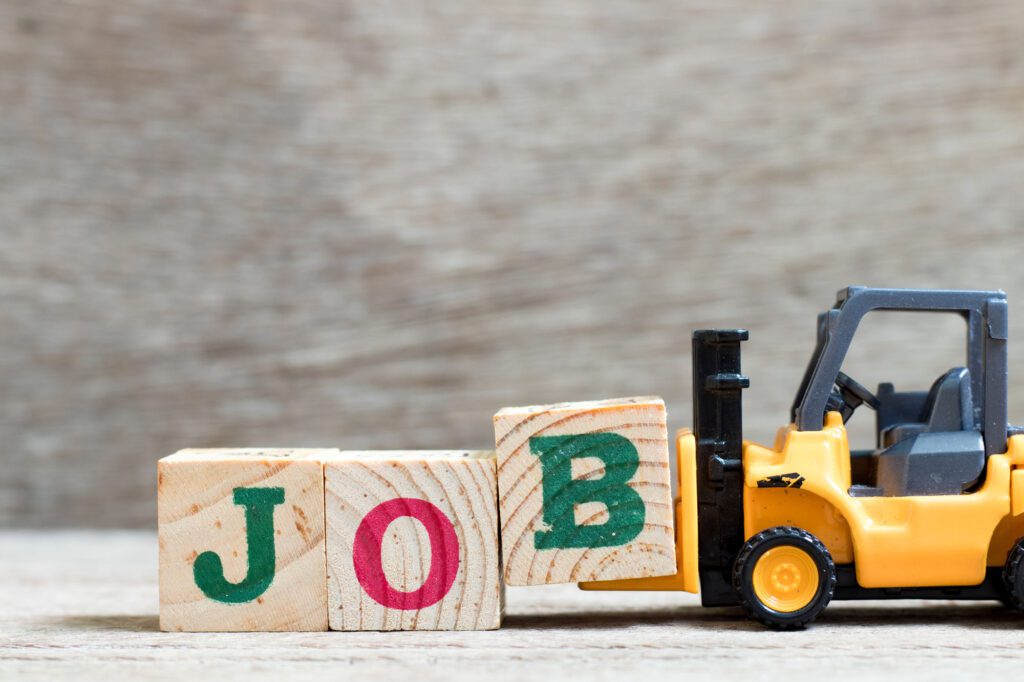 Toy forklift hold letter block B to complete word job on wood background