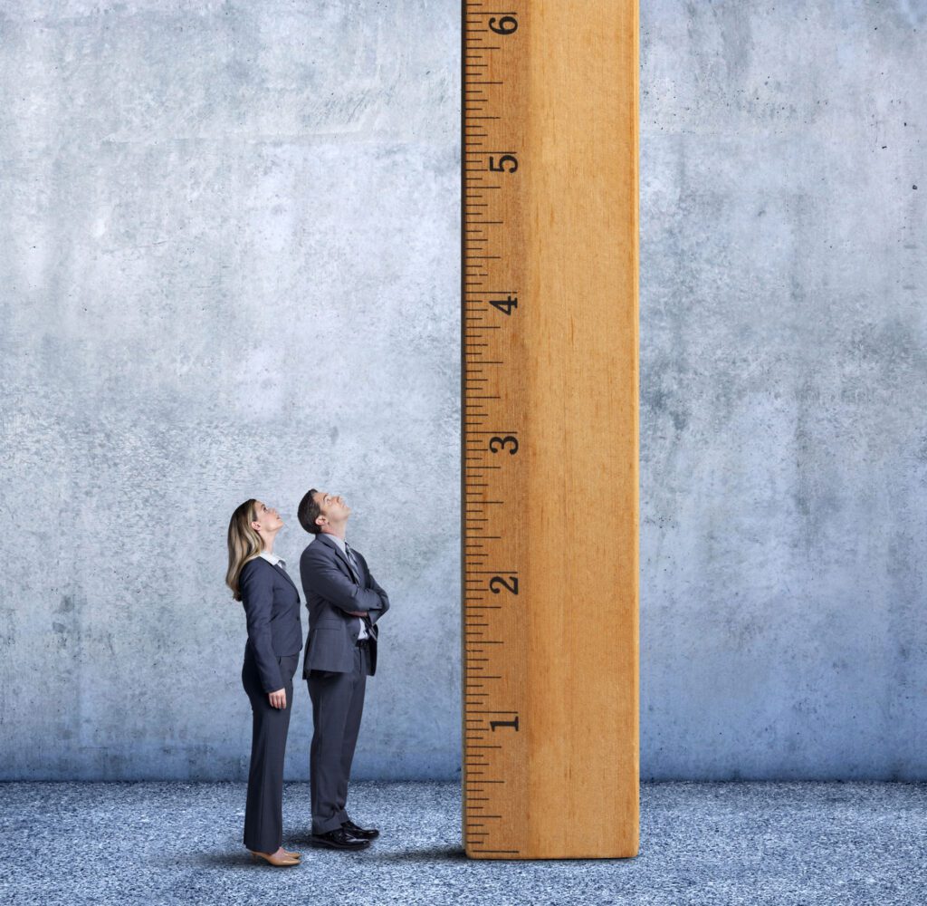 Businessman And Businesswoman Looking Up A Tall Ladder