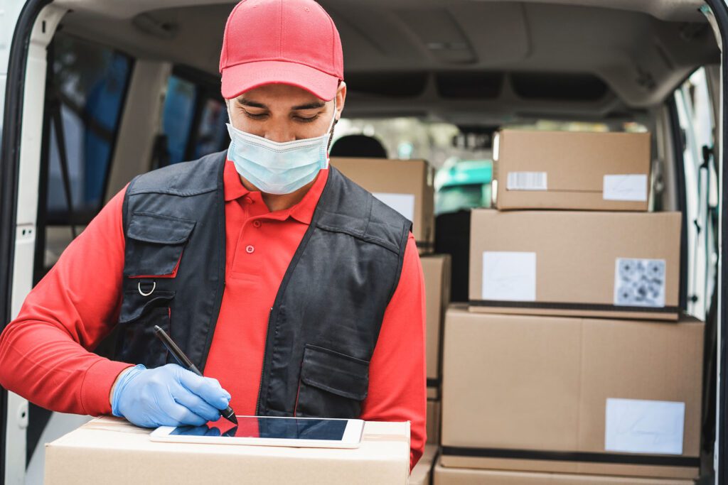 Delivery man writing receipt during coronavirus pandemic time – Covid-19 work measures and social distance concept – Focus on man face