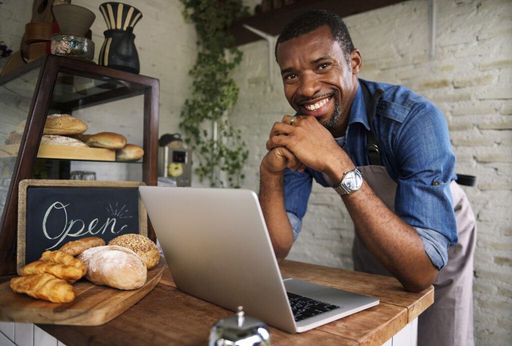 A man standing in front of a laptop and smiling.