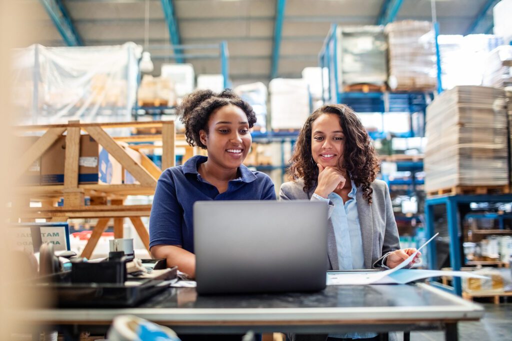 Warehouse employees using laptop in plant