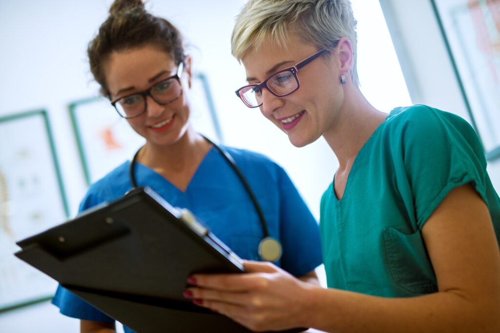 Close up view of two professional nurses with eyeglasses checking the patient papers in a doctors office.