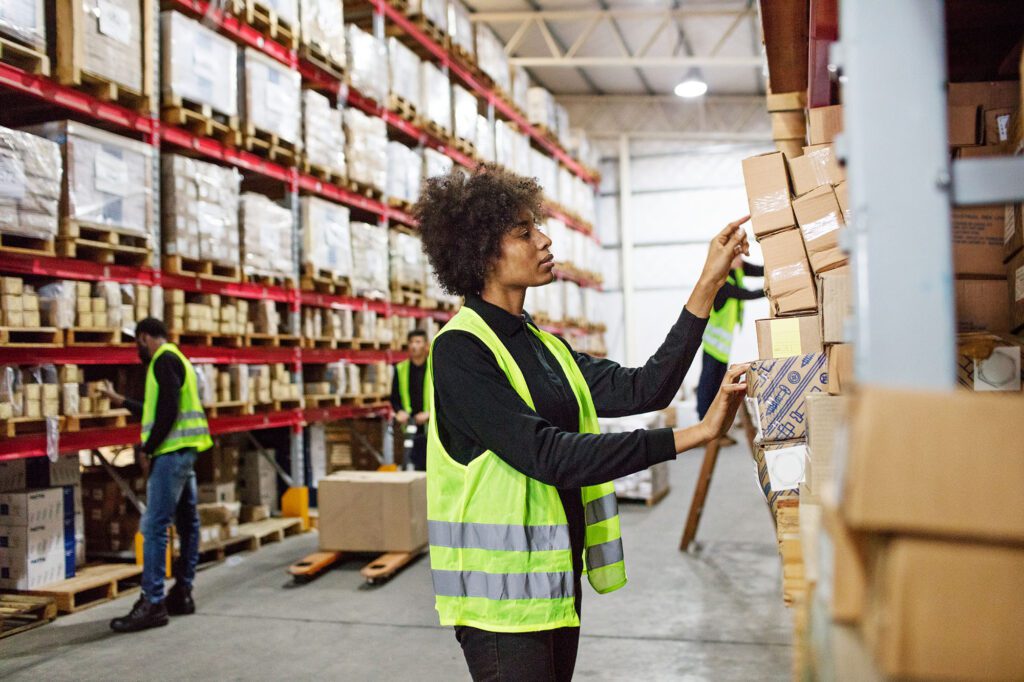 Female warehouse worker stacking boxes onto the rack