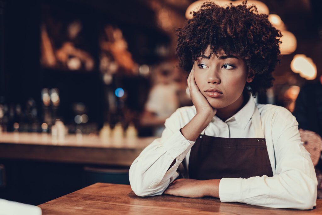 Tired young lady looking aside and sitting over table