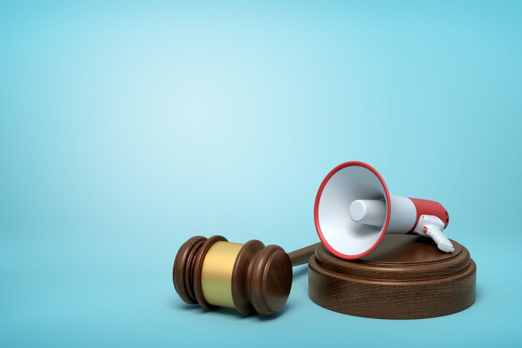 3d rendering of megaphone on round wooden block and brown wooden gavel on blue background