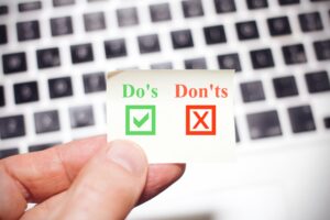 Business man holds up a yellow note sign with the words dos and don'ts