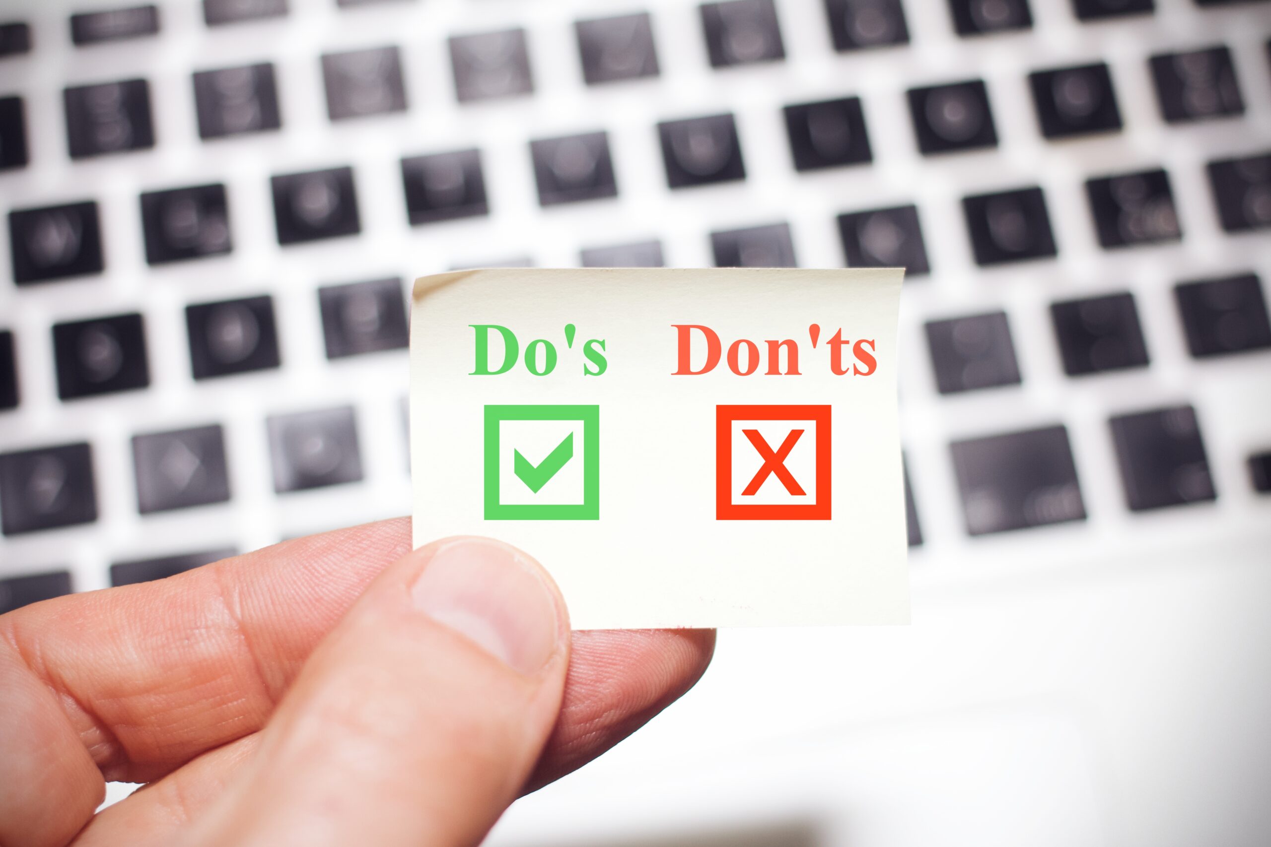 Business man holds up a yellow note sign with the words dos and don'ts
